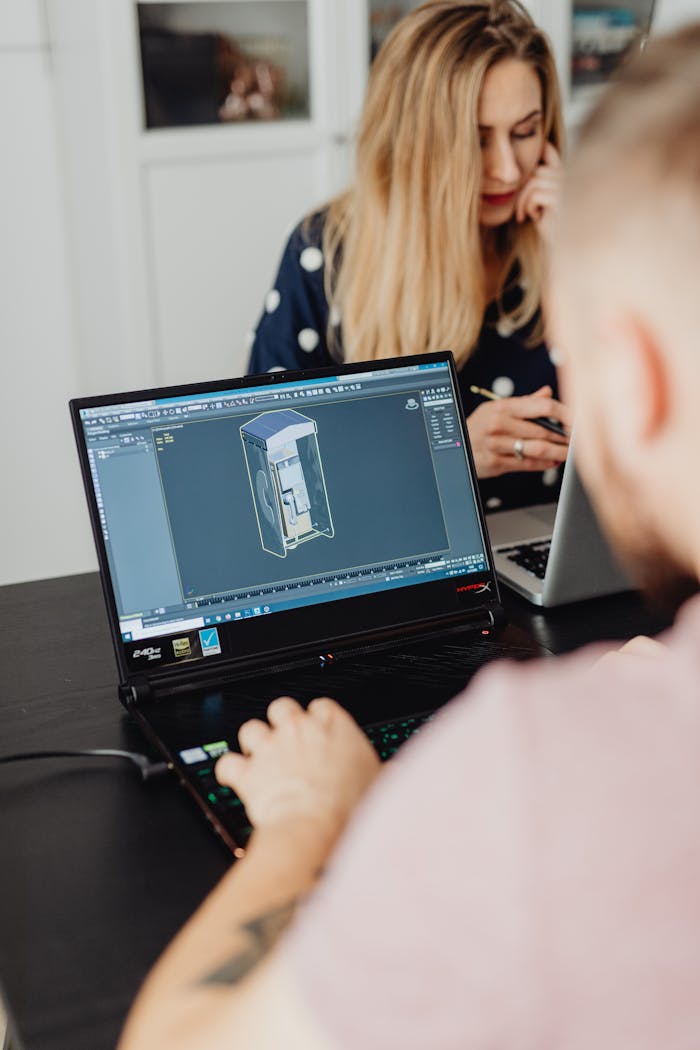 embark Two colleagues working on laptops indoors, focusing on 3D modeling software.